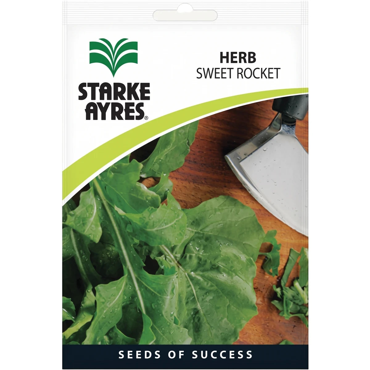 Starke Ayres Herb Sweet Rocket seed packet with fresh green rocket leaves and a small silver gardening tool on a wooden