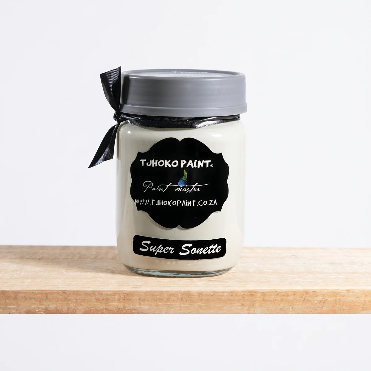 Off-white Super Sonette 250ml Tjhoko Paint chalk paint in a glass jar with a black label and gray lid, on a wooden shelf.