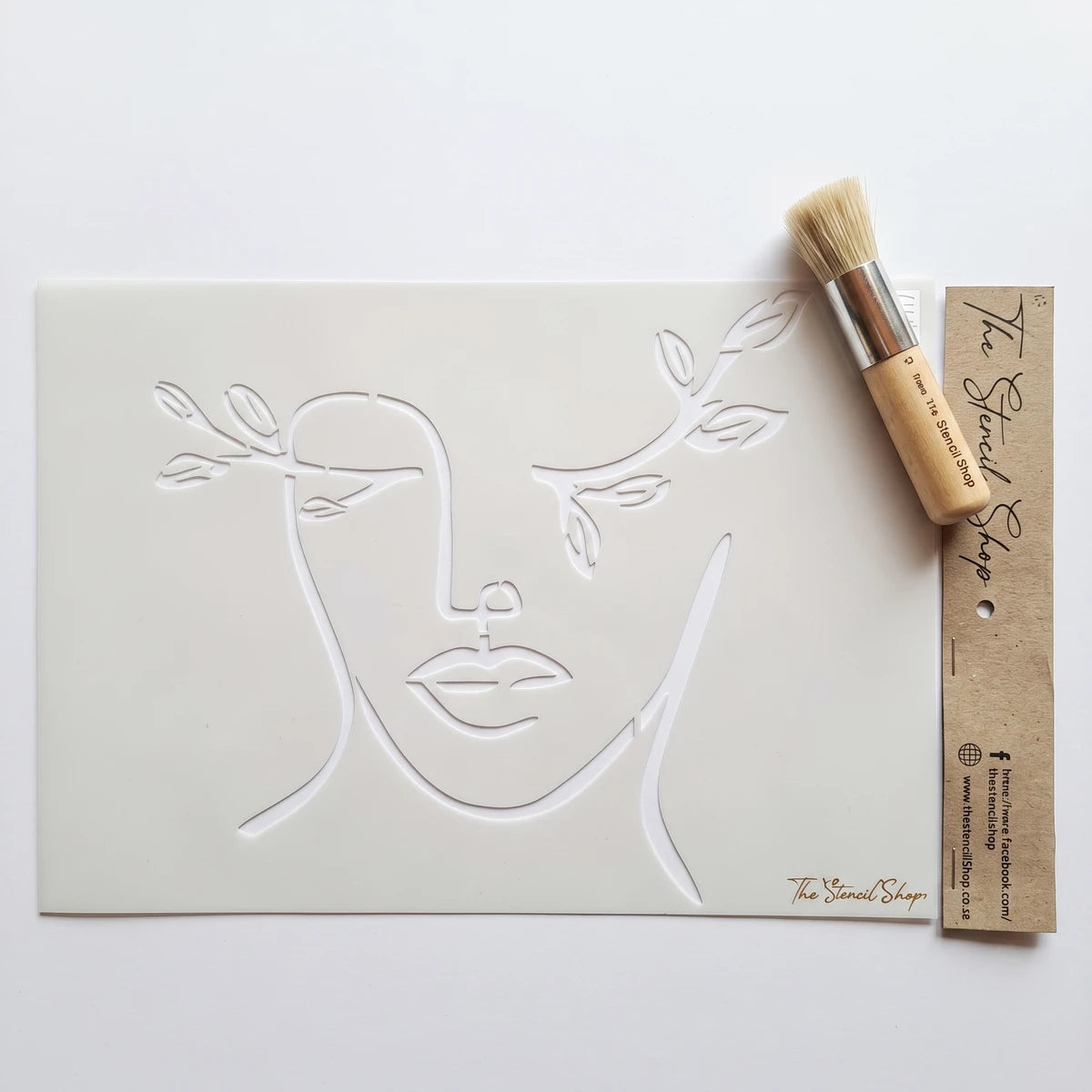 Sweet Elegance A4-23 Stencil 70, a white stencil with minimalist line art of a face and branches, next to a wooden stencil