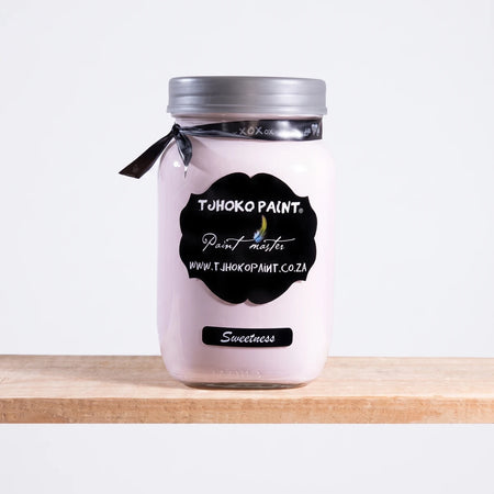 Sweetness 1L pale pink chalk paint in a clear glass jar with a silver lid and black label, sitting on a wooden shelf.