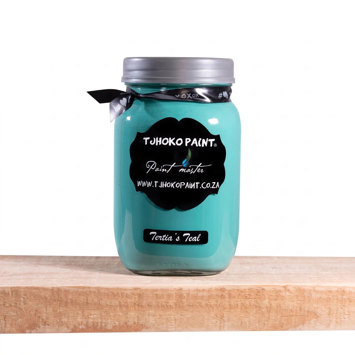 Tertia's Teal 1L Tjhoko Paint chalk paint in a glass jar with a black label, sitting on a wooden shelf.