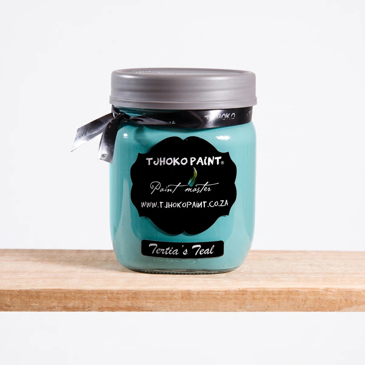 Tertia's Teal 500ml chalk paint in a glass jar with a black label and ribbon, sitting on a wooden shelf.