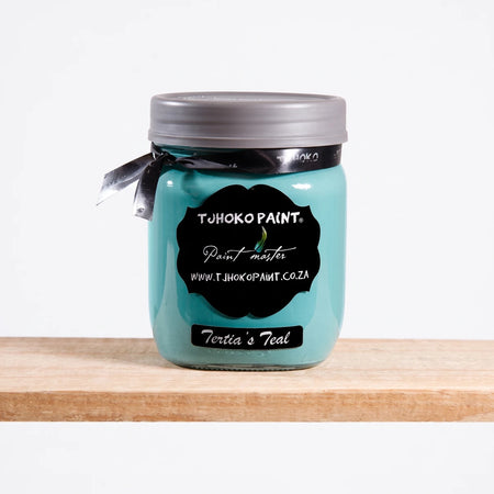Tertia's Teal 500ml chalk paint in a glass jar with a black label and ribbon, sitting on a wooden shelf.