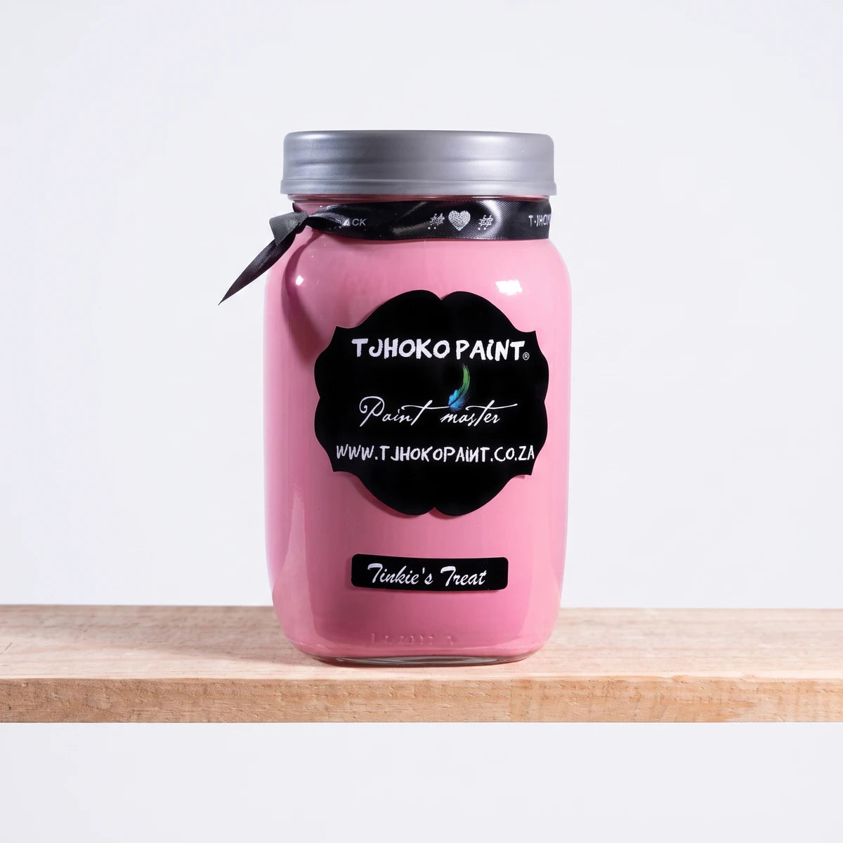 Tinkie's Treat 1Litre Chalk Paint in a pink glass jar with a silver lid and black labels, displayed on a wooden shelf.