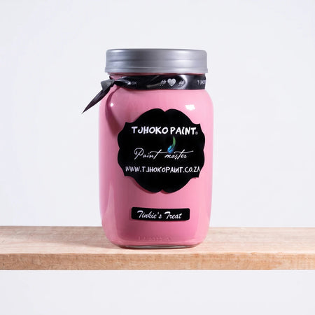 Tinkie's Treat 1Litre Chalk Paint in a pink glass jar with a silver lid and black labels, displayed on a wooden shelf.