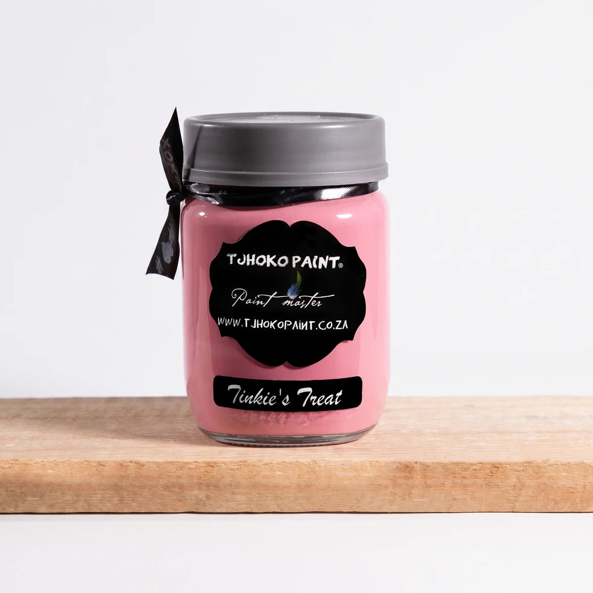 Pink Tinkie's Treat 250ml chalk paint in a glass jar with a gray lid, resting on a wooden surface.
