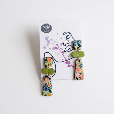 Tjhoko Asgat Se Fynbos floral enamel dangling earrings displayed on a white card with abstract design.
