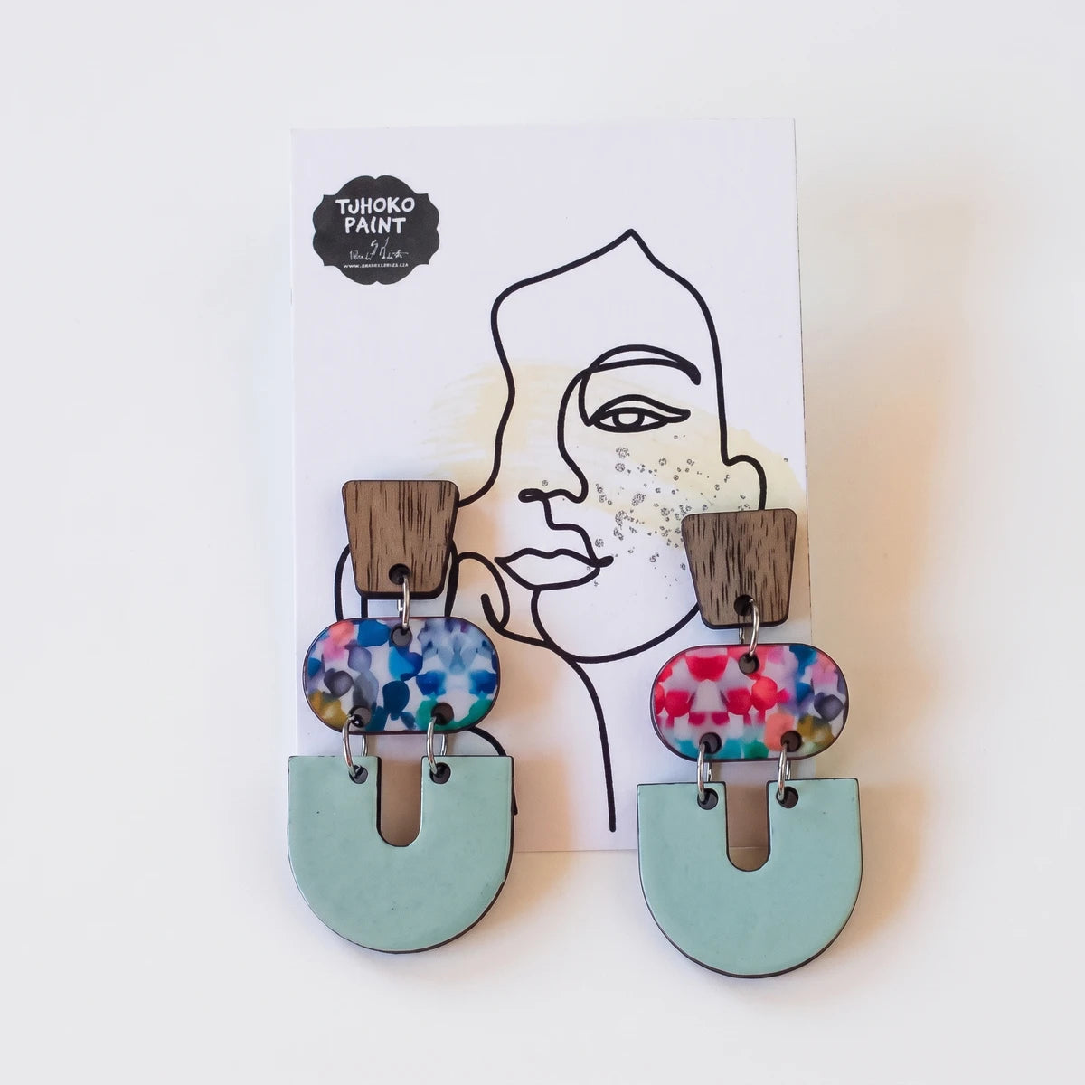 Two Tjhoko Fine Colorful Art Earrings displayed on a card, featuring rectangular wooden tops, speckled acrylic, and mint