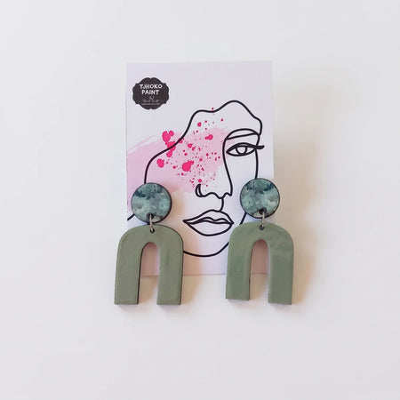 A pair of Tjhoko Olivia's Floral Art earrings featuring sage green arch shapes and circular floral print studs, displayed on