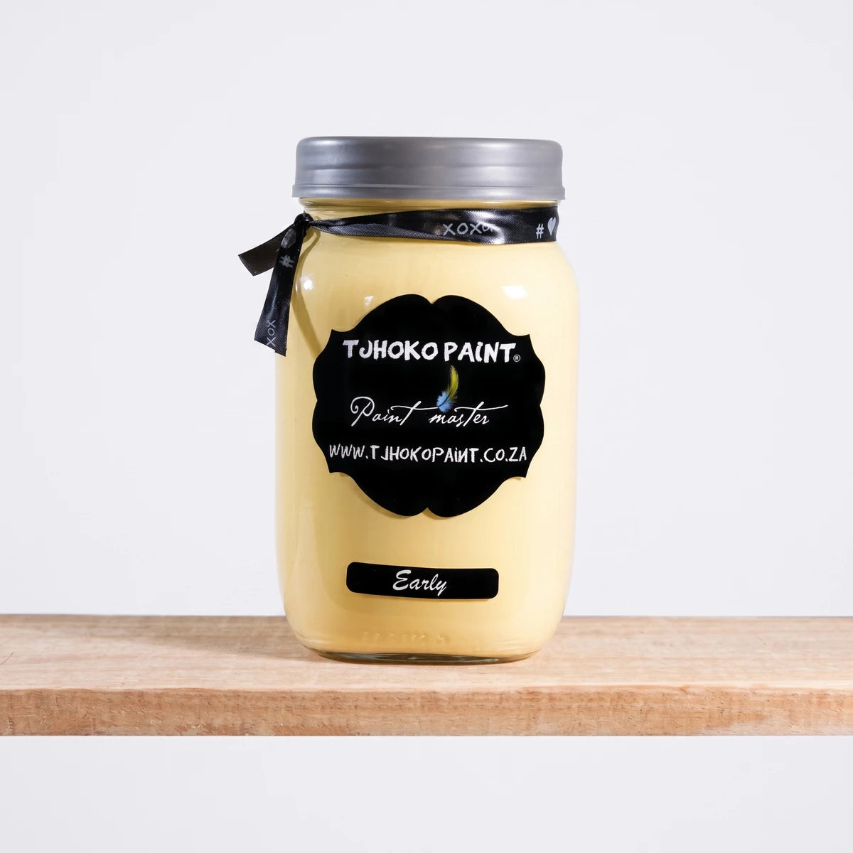 Early 500ml Chalk Paint jar by Tjhoko Paint on a wooden shelf, featuring a pale yellow color.