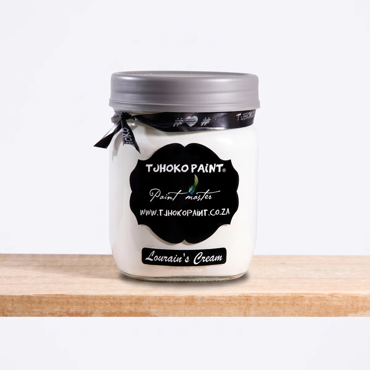 Lourain's Cream 500ml chalk paint by Tjhoko Paint in a clear glass jar with a gray lid and decorative black ribbon.