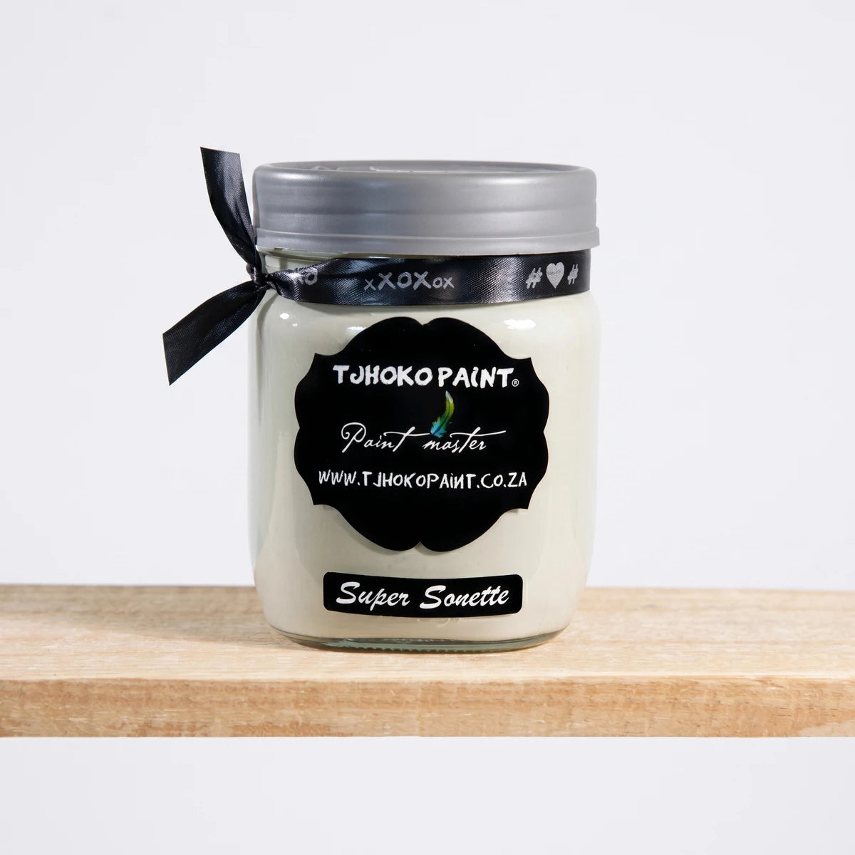 Tjhoko Paint Super Sonette 500ml chalk paint jar with a silver lid and black ribbon on a wooden shelf.