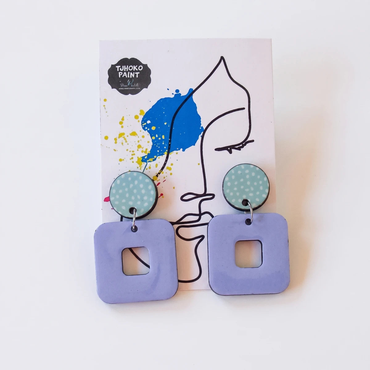A pair of Tjhoko Paint Trish dangle earrings featuring light blue dotted round tops and lavender square drops with cutouts,