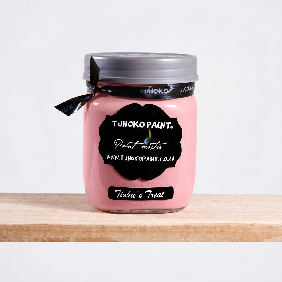 Tjohoko Paint Tinkie's Treat 500ml chalk paint in a clear glass jar with a gray lid and black ribbon, displayed on a wooden