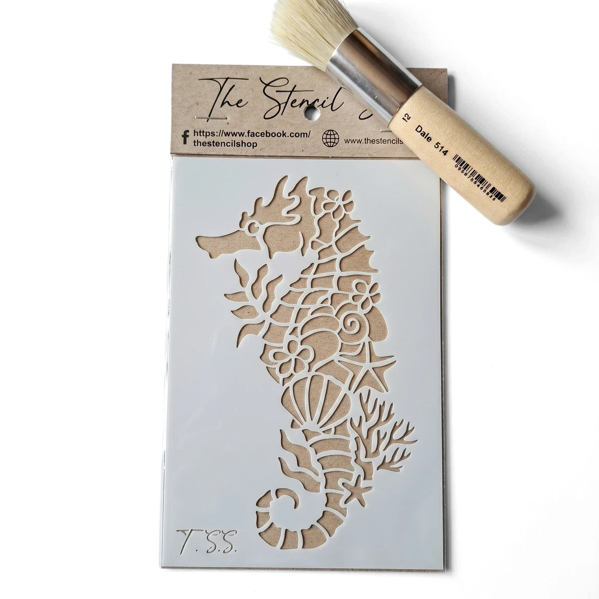 White plastic seahorse paint stencil with intricate shells and coral design, shown with a natural bristle stencil brush.