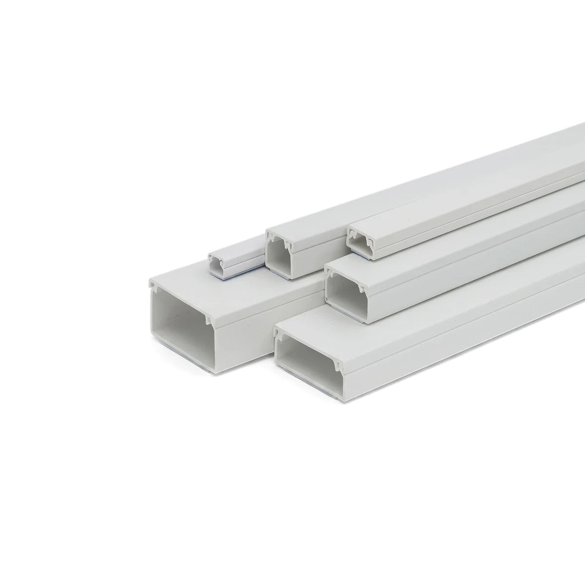 White PVC electrical trunking in various sizes, arranged diagonally on a white background, showcasing the open channels.